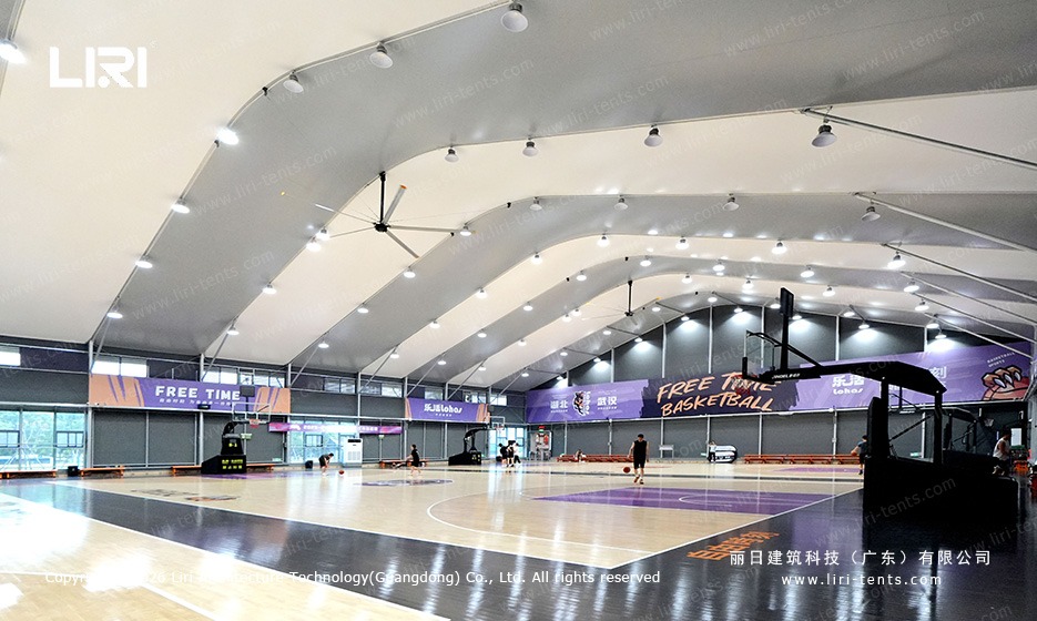 Full basketball court inside sports marquee - multiple hoops, spectator seating, professional floor