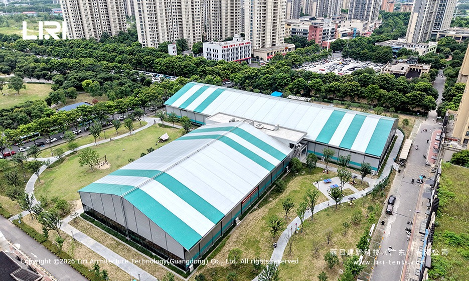 Aerial view sports marquee complex - green white striped clear span tent, basketball facility, drone shot