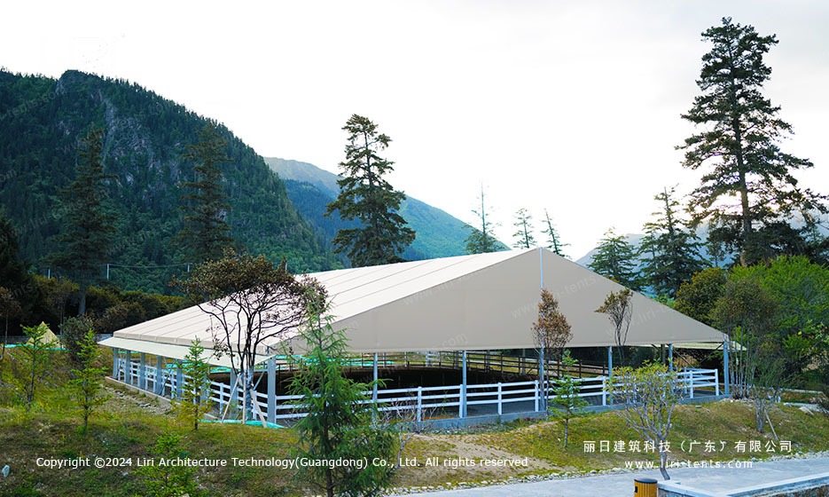 30m x 35m equestrian arena marquee on a sloped lawn, mountain valley backdrop