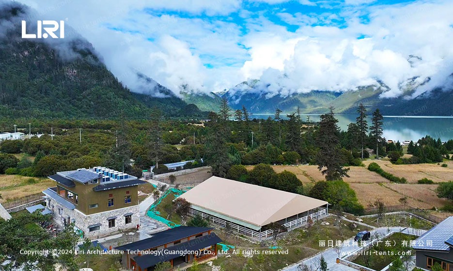 Aerial view of the equestrian marquee next to the resort building, lake and mountains in the background