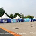 Multi-zone exterior wide shot showing pagoda tents along the race circuit with FIA Formula E branding