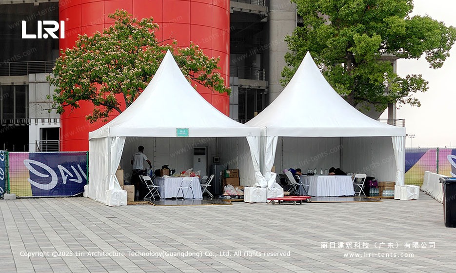 Refreshment and dining area inside twin high peak pagoda tents with white sidewalls at the Shanghai E-Prix