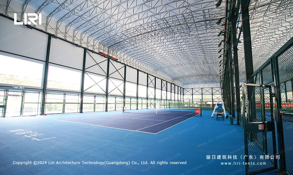 Interior of tennis marquee with blue court surface and bright LED lighting