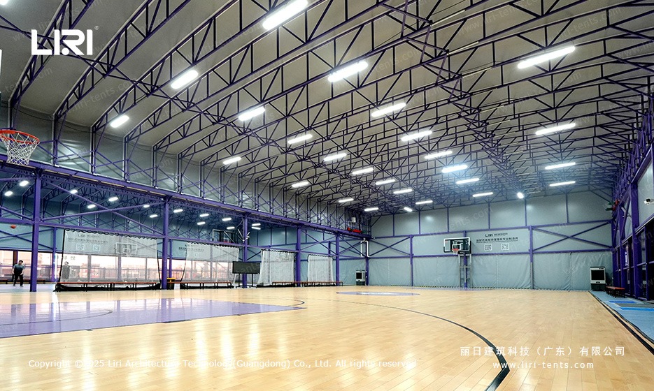 Inside purple gable marquee aluminum truss structure over full size basketball court with badminton nets