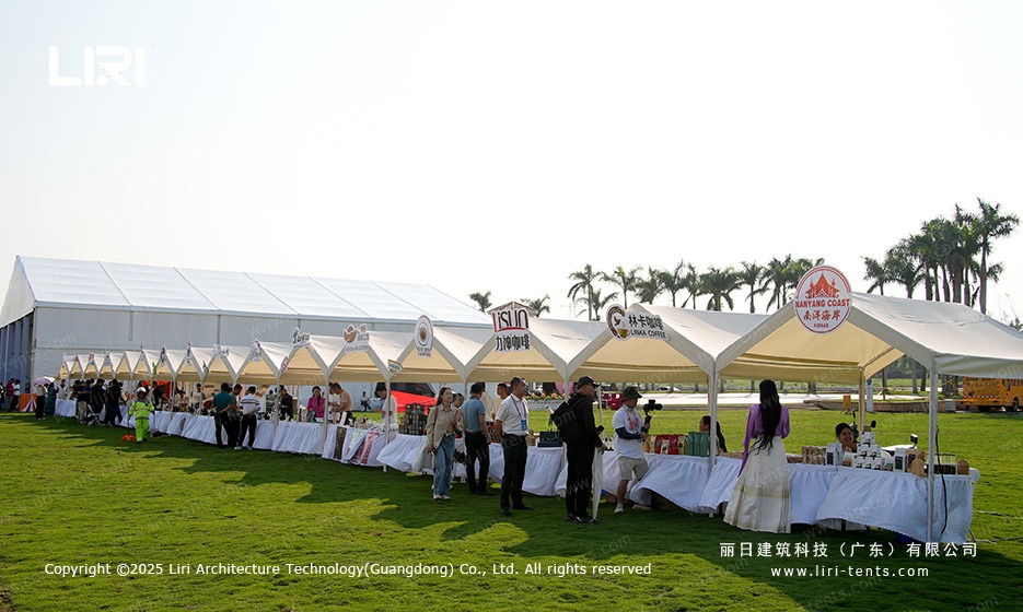 Outdoor festival tent setup with clear span hall and pagoda vendor booths on tropical lawn