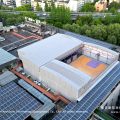 Purple gable twin peak marquee aerial drone view over rooftop basketball court next to solar panels