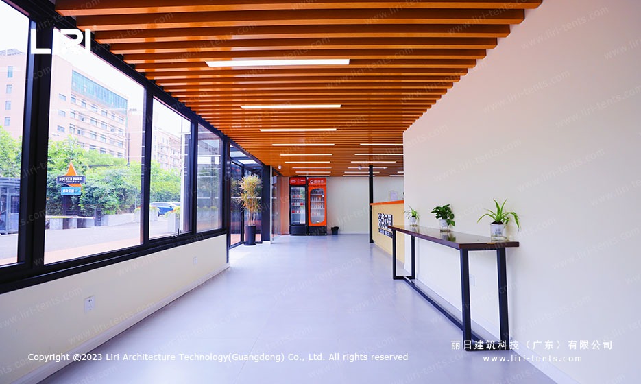 Internal corridor of marquee sports hall with vending machines and wood slat ceiling