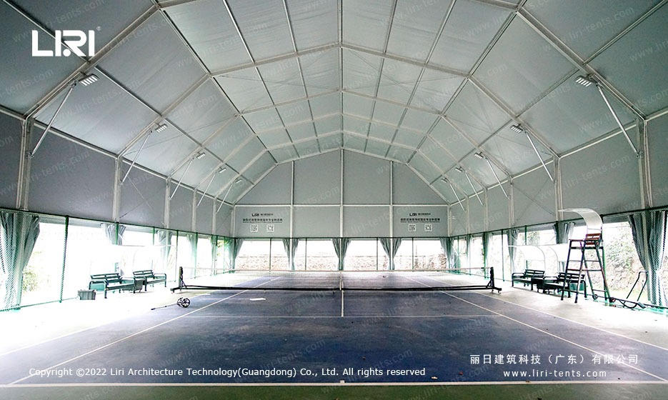 Tennis court interior under clear-span marquee with arcum roof profile