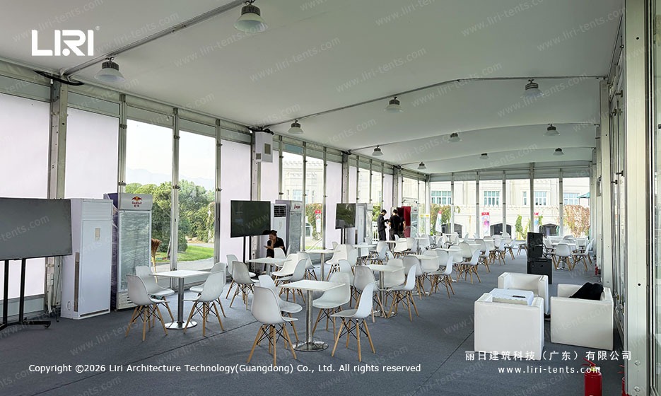 Tables and lounge seating inside the glass-sided golf event marquee