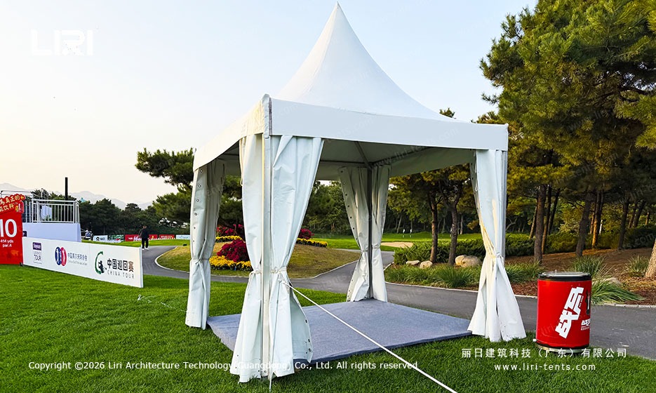 White peaked pagoda tent beside a golf course path
